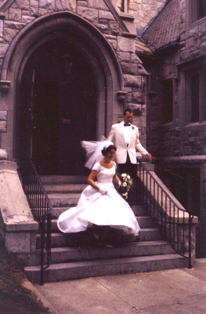 Bride and groom walking down church steps in their wedding outfits