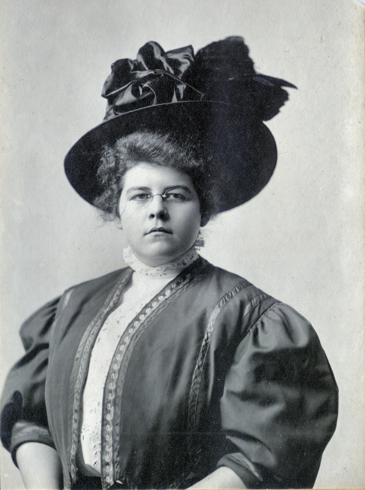 Bust of woman in striking hat and glasses